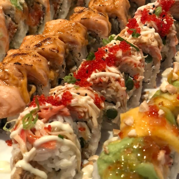 Close-up of various Sushi Avenue sushi rolls, including salmon, crab, and avocado with roe.